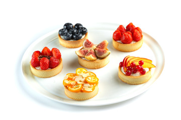 tartlets with fruits and berries in a plate on an isolated white background