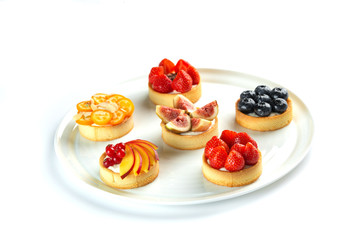 tartlets with fruits and berries in a plate on an isolated white background