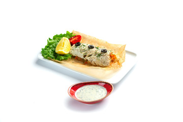 baked fish fillet with tomato, lemon, herbs and sauce on an isolated white background
