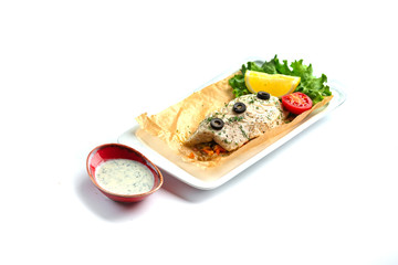 baked fish fillet with tomato, lemon, herbs and sauce on an isolated white background