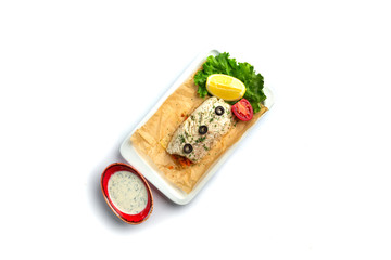 baked fish fillet with tomato, lemon, herbs and sauce on an isolated white background