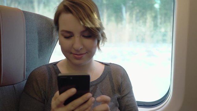 Young girl using smartphone, serfing internet. Passenger in train.
