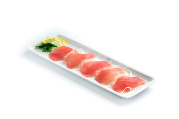 pieces of red fish with lemon and herbs on a rectangular plate on an isolated white background