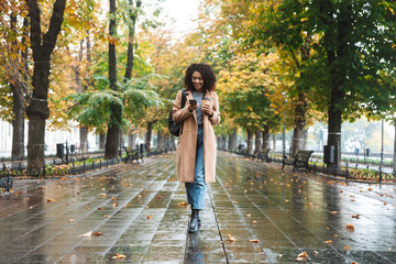 Beautiful young african woman wearing coat walking outdoors