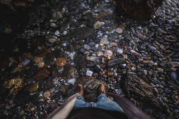 Shoes from above on rock with water