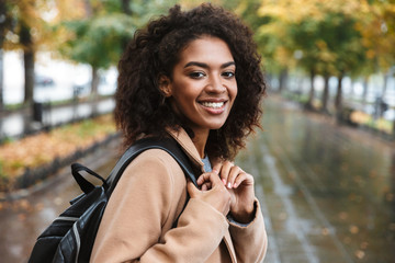 Beautiful young african woman wearing coat walking outdoors