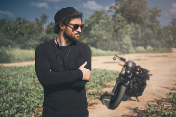 Fototapeta premium Portrait of handsome young man with black motorcycle