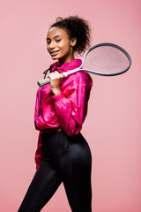 beautiful smiling african american sportswoman holding tennis racket and looking at camera isolated on pink © LIGHTFIELD STUDIOS