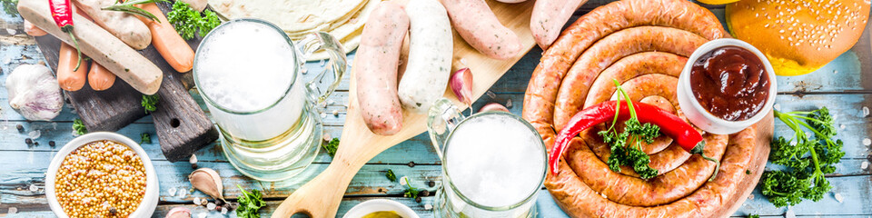 Different bbq picnic party food with beer  various grilled sausages, burger buns, flat taco bread, beer, old wooden background copy space