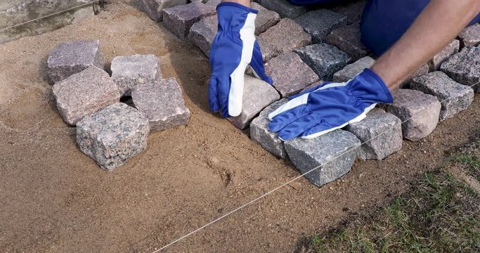 garden path pavement - worker laying granite cobblestone