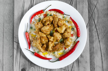 chicken in sweet and sour sauce and rice with vegetables and pepper on a white plate black and white background