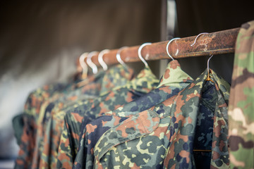 Camouflage military jackets haning on a rusty clothing rack