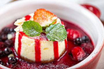Homemade strawberries cheesecake with berries  syrup and mint on white bowl