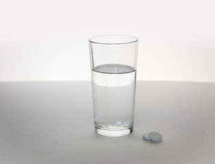 clear glass and pills on white table