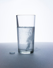 clear glass and pills on white table