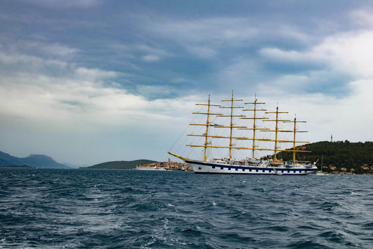 large ive masts sailing ship in the Adriatic Sea near Korchula town on dark cloud sky backgound