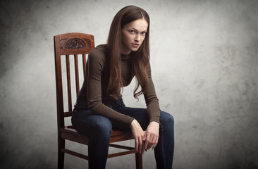 pretty brunette woman is sitting on a chair in studio
