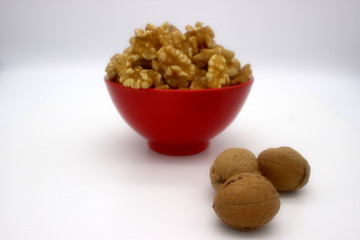Walnut Kernels In Red Bowl (Other Names: Juglans Regia, Persian Walnut, English Walnut, Circassian Walnut). Isolated Image On A White Background