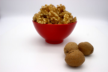 Walnut Kernels In Red Bowl (Other Names: Juglans Regia, Persian Walnut, English Walnut, Circassian Walnut). Isolated Image On A White Background