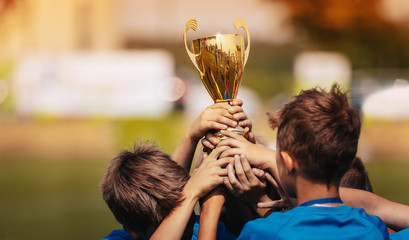 Children Celebrating Sport Success Outdoor. Boys Holding Golden Cup