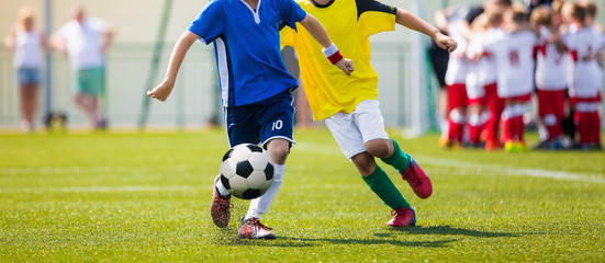 Obraz premium Junior Soccer Teams During Running Duel. Football Game For Youth Players. Boys Playing Soccer Match on Football Pitch. Football Stadium and Team Huddling in the Background
