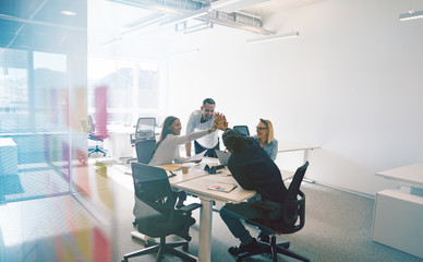 Diverse coworkers enthusiastically high fiving together inside o