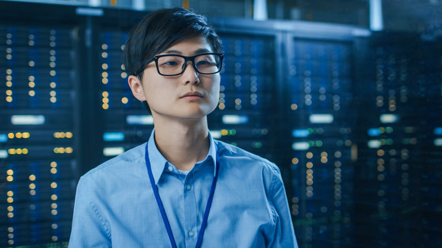 In the Modern Data Center: Portrait of IT Engineer Working With Touch Screen Device. In the Background Working Server Racks with Blinking LED Lights. - Powered by Adobe
