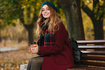 Lovely young woman wearing coat and beret sitting