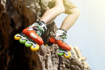 legs in skates of a girl in a rock and a building