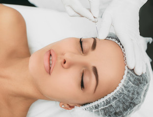 beautician installs the mesothreads in the face of the woman. Anti-aging cosmetic procedures