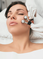 Obraz na płótnie Canvas Beautiful woman receiving facial microcurrent procedure for lifting face. Facial rejuvenation and facelift with microcurrent therapy