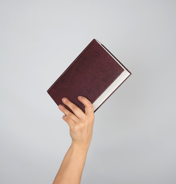 hand holds a closed book in hardcover