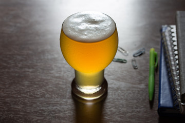 Glasses of beer and office accessories on wooden table