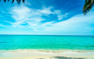 Fototapeta premium Golden sand beach by the sea with emerald green sea water and blue sky and white clouds. Summer vacation on tropical paradise beach concept. Ripple of water splash on sandy beach. Summer vibes.