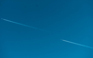 Two airplane with white condensation tracks. Jet plane on clear blue sky with vapor trail. Travel by aeroplane concept. Trails of exhaust gas from airplane engine. Aircraft with white stripes.