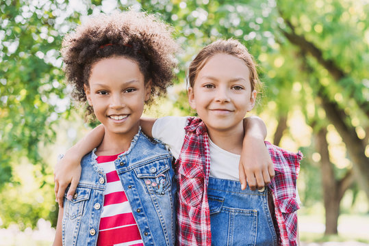 Two Little Girls Hugging In The Park. Diverse Multi Ethnic Kids Friends Playing Together Outdoor. Summer Fun, Friendship, Diversity, Vacations Concept	