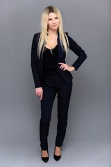 Portrait of happy smiling young cheerful businesswoman standing. Success in business concept studio shot talking to a client. Gray suit.