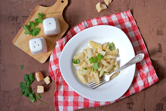 Roasted Jerusalem artichoke with cheese and parsley on a white plate. Healthy food. Top view.