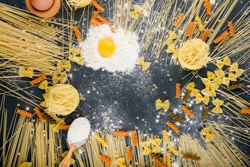 preparing pasta, eggs, flour, various types of pasta, spaghetti, on dark background.from above.