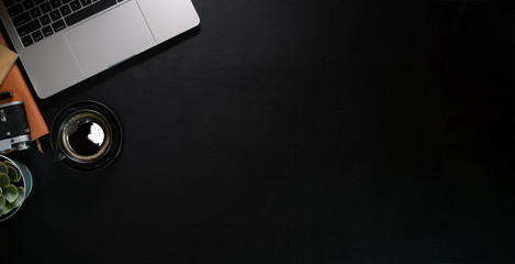 Dark leather desk table with laptop and supplies. Top view with copy space.