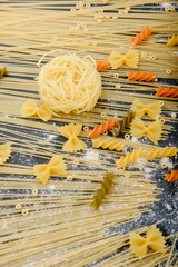 preparing pasta, eggs, flour, various types of pasta, spaghetti, on dark background.from above.