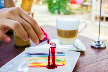 Colorful cheesecake and strawberry syrup on plate at coffee cafe