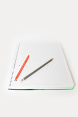 multi-colored pencils orange green gray on a white background notebook