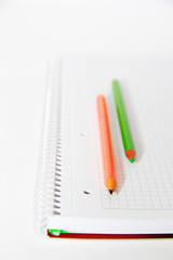 multi-colored pencils orange green gray on a white background notebook