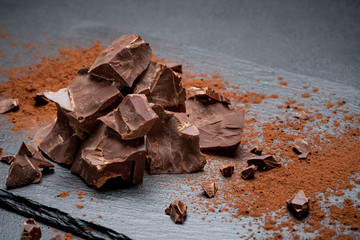 Dark or milk organic chocolate pieces on dark concrete backgound