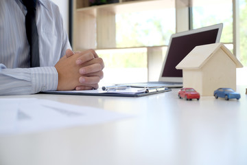 Sales manager giving advice application form document, considering mortgage loan offer for car and house insurance.