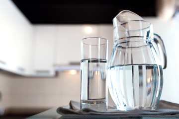 A glass of fresh water with crafin on the background of a modern kitchen.