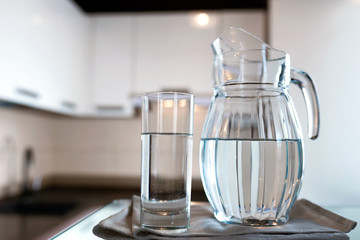 A glass of fresh water with crafin on the background of a modern kitchen.
