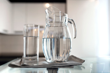 A glass of fresh water with crafin on the background of a modern kitchen.