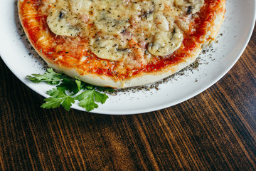 Hot pizza slice with melting cheese on a wooden table.